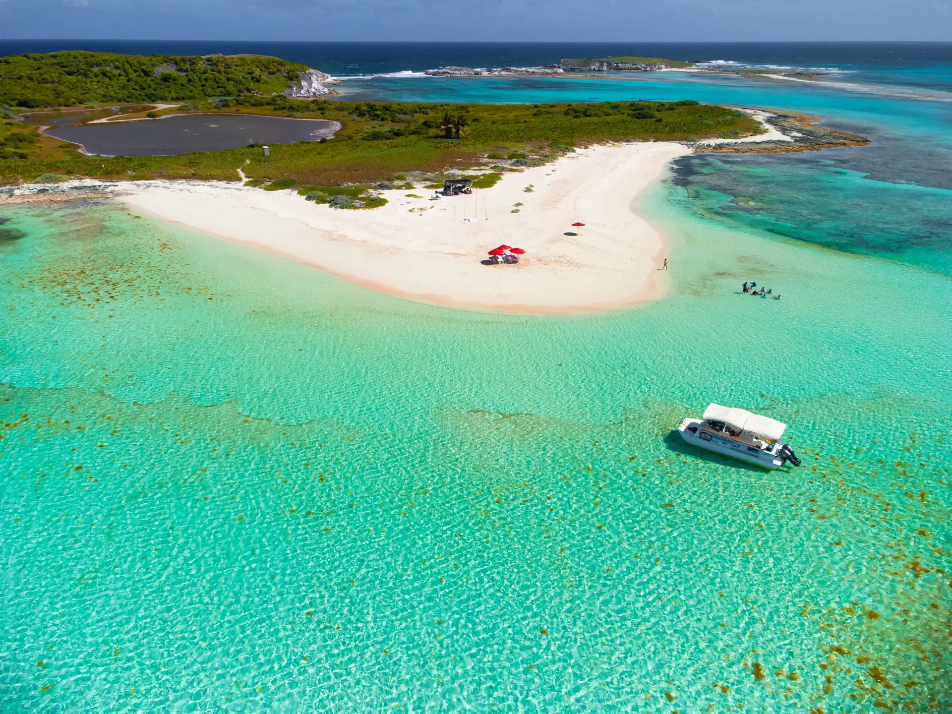 Aerial view of a boat in turquoise sea against a beautiful beach in San Salvador, The Bahamas