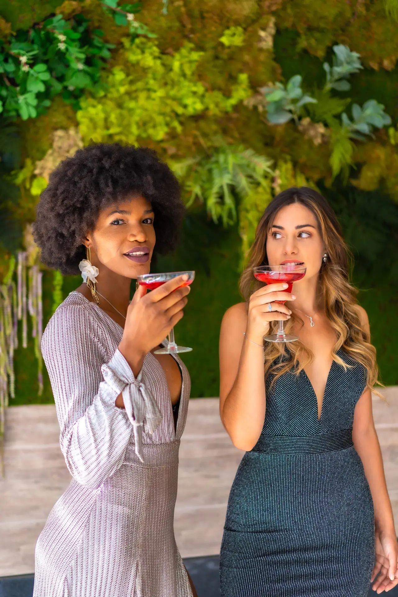 Two friends in gala dresses having a cocktail at a party in a hotel, lifestyle